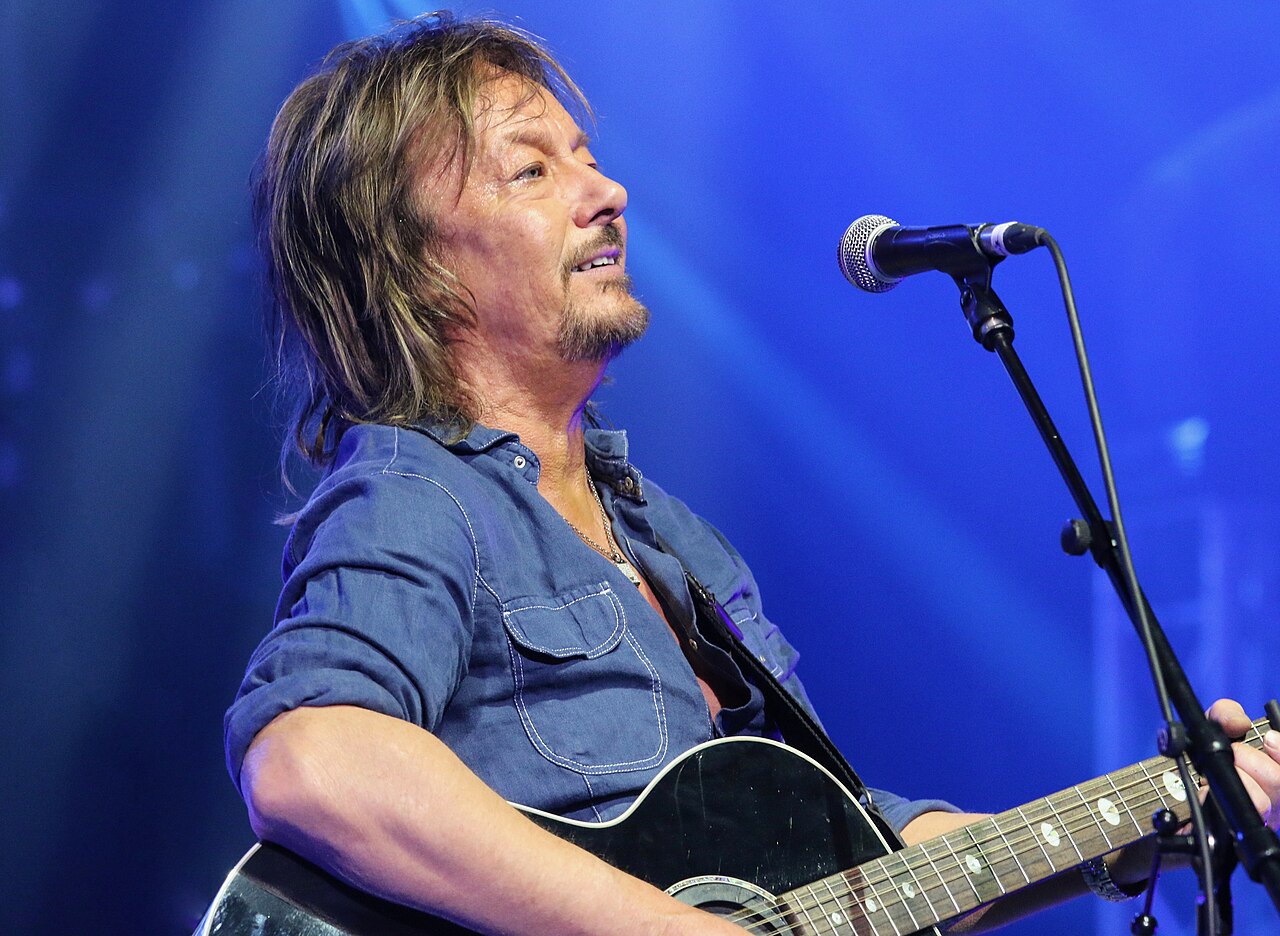Chris Norman bei einem Live-Auftritt, mit Mikrofon in der Hand.