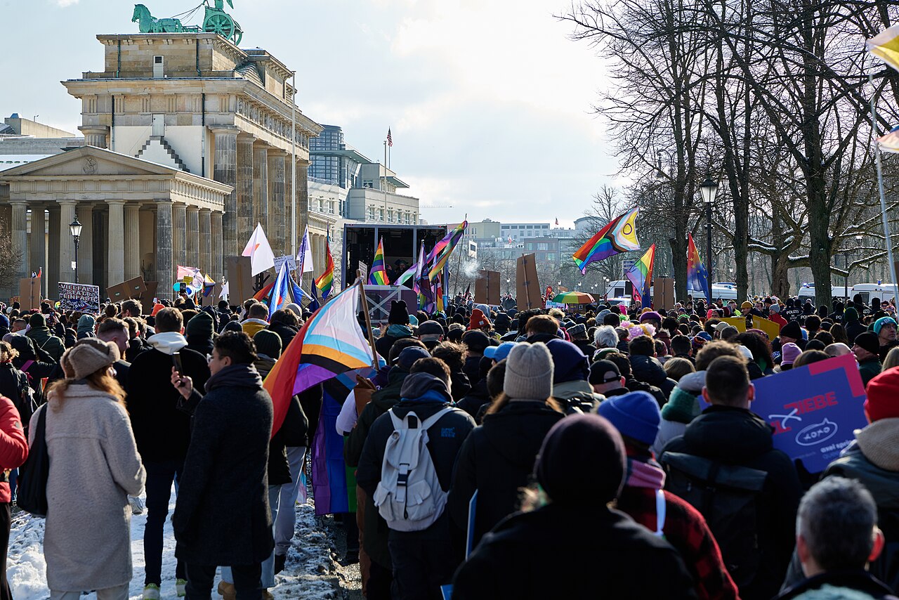 Menschen mit Regenbogenfahnen vor dem Brandenburger Tor in Berlin