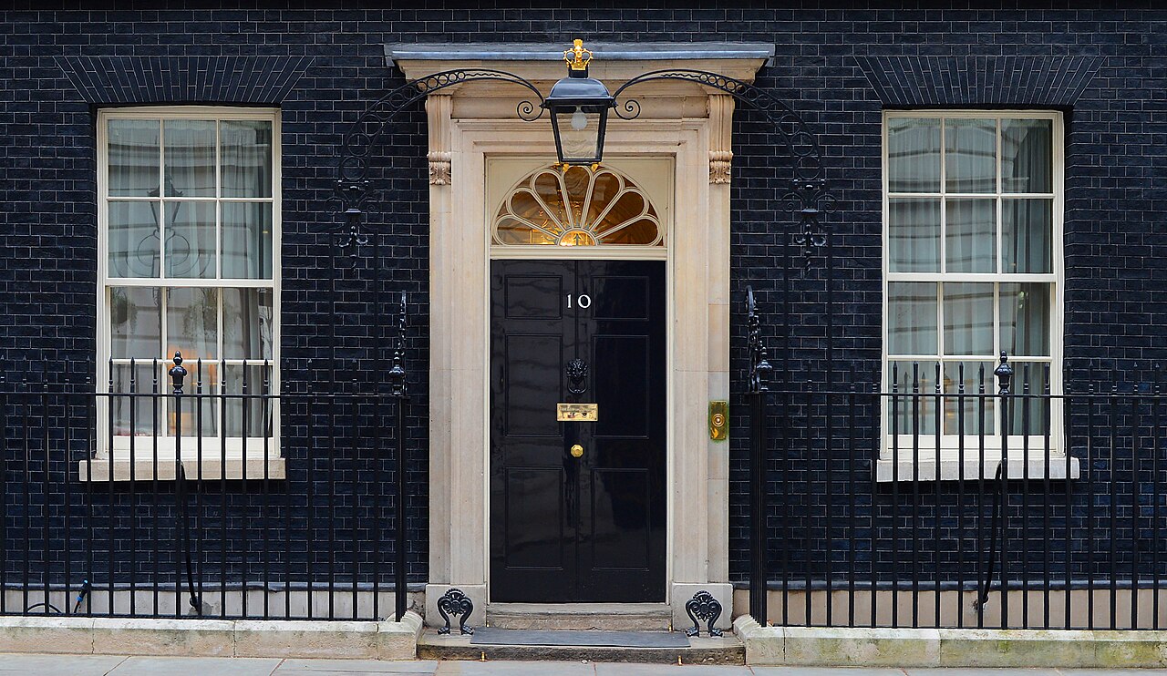 Eingangsbereich der 10 Downing Street in London, dem Amtssitz des britischen Premierministers, mit der schwarzen Tür und der weißen Ziffer 10.