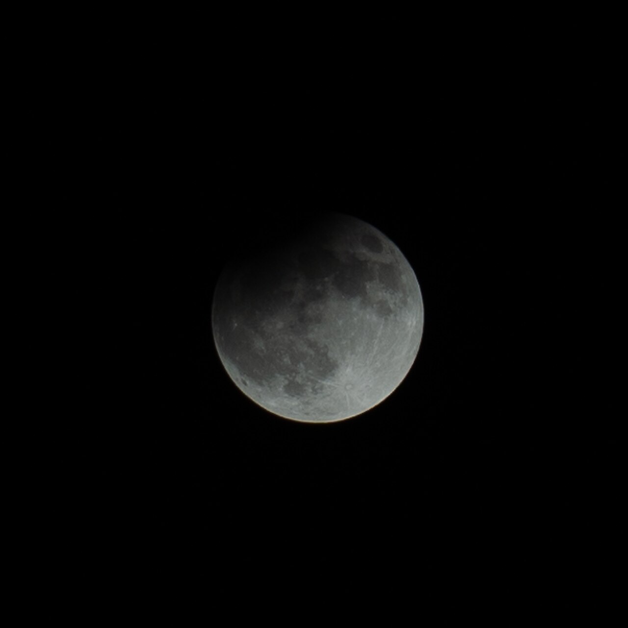 Partielle Mondfinsternis, aufgenommen im September 2024. Der Mond ist überwiegend im rötlichen Kernschatten der Erde, ein kleiner Rand bleibt hell.