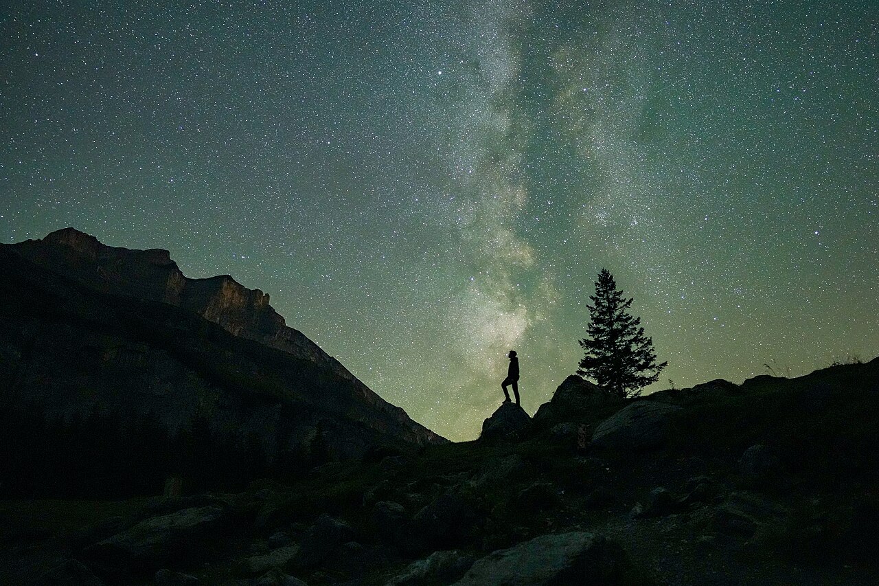 Person blickt auf den Sternenhimmel während der Perseiden-Nacht, Milchstraße im Hintergrund am Oeschinensee