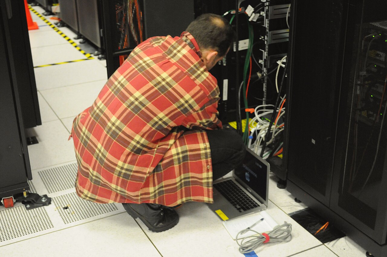 Techniker mit Laptop vor einem Server-Rack im Rechenzentrum.