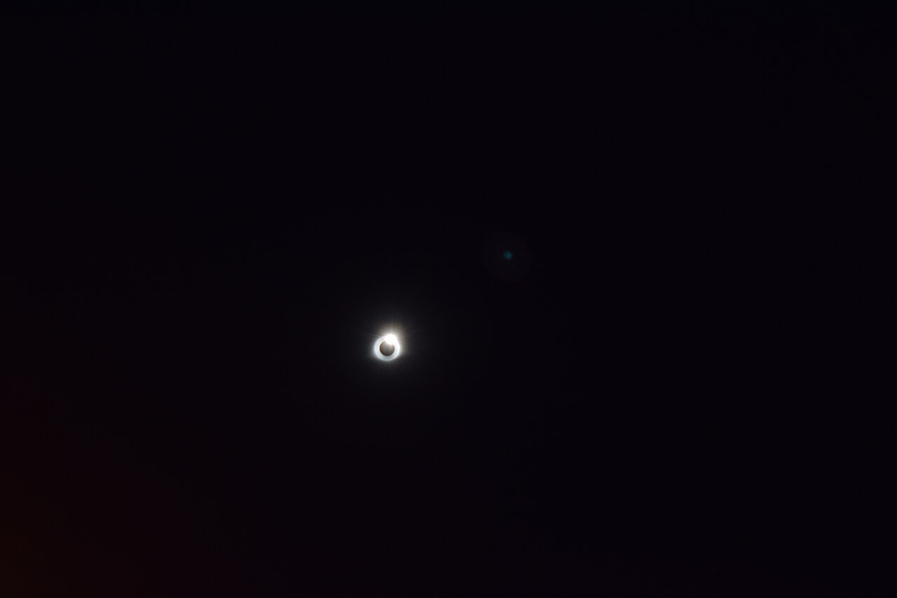 Diamantring-Effekt kurz vor der Totalität einer Sonnenfinsternis - die schmale Sonnensichel leuchtet am Rand der abgedunkelten Mondscheibe auf.