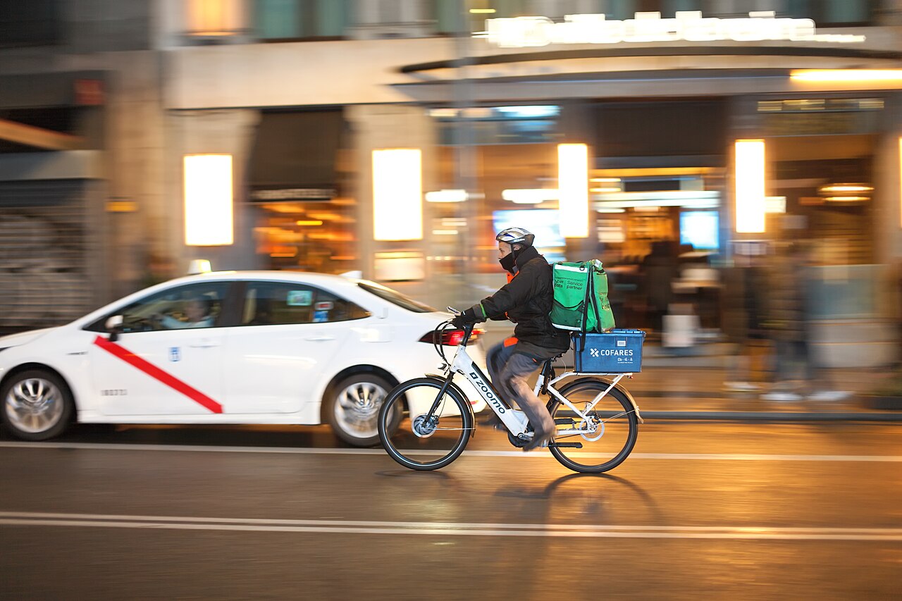 Ein Uber-Eats-Fahrradkurier mit Rucksack auf der Gran Vía in Madrid.